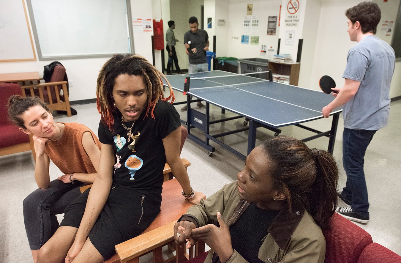 三个学生在其中一个学生休息室聊天，另外两个在打乒乓球.