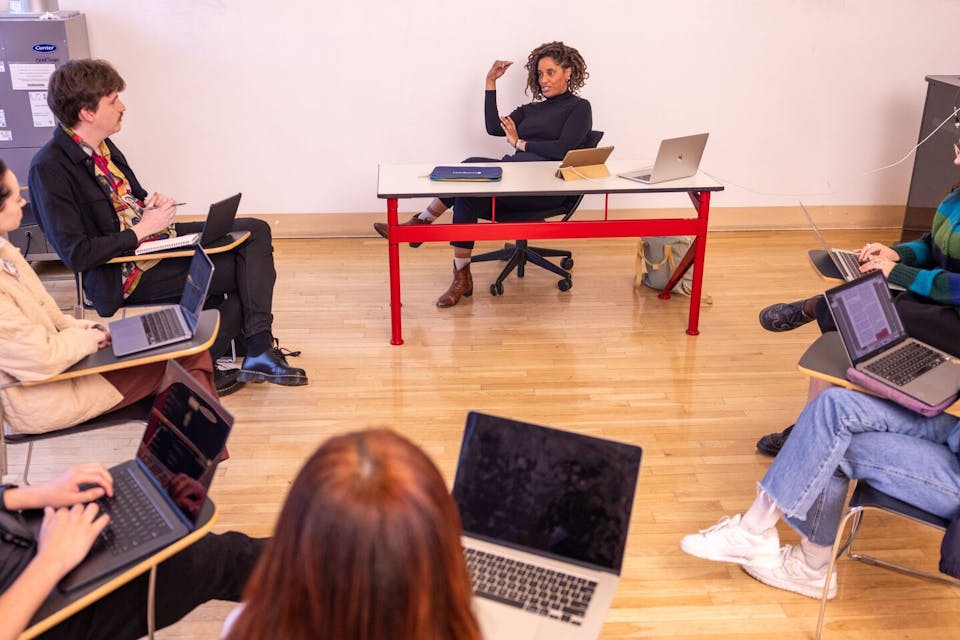 A teacher instructs a class seated in a circle 