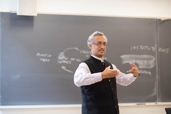 Economics-Faculty-Sanjay-Reddy-Arms-Up-Chalkboard