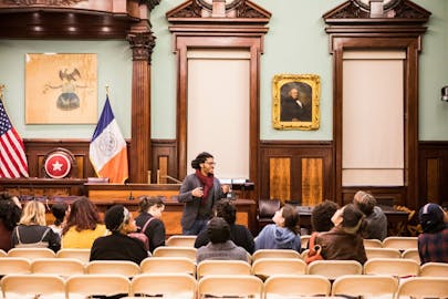 Students sit in a auditorium as part of a museum tour and lecture.