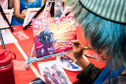 A student paints Gnarls the Narwhal, New School mascot.