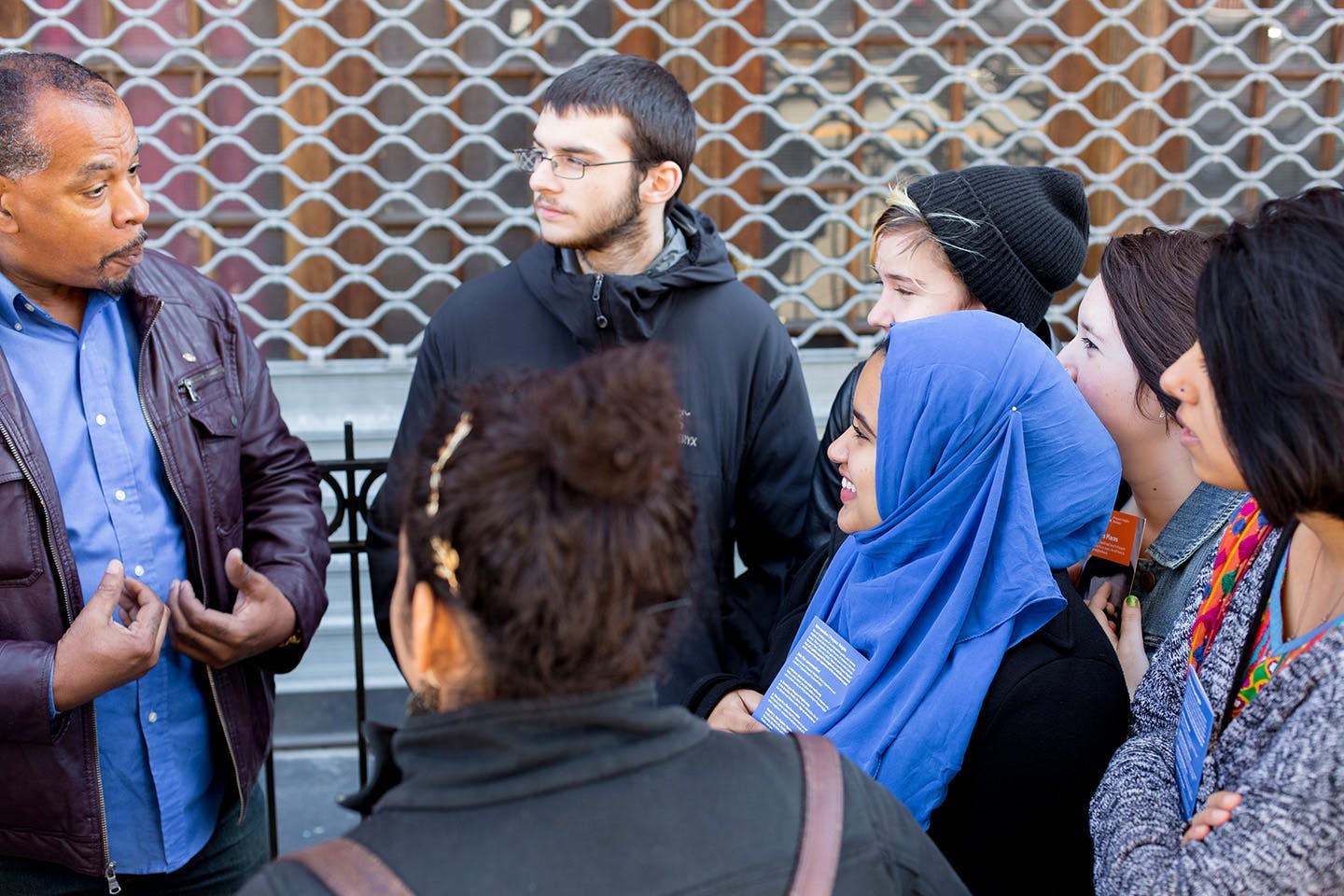 Students listen to a teacher outside a storefront.