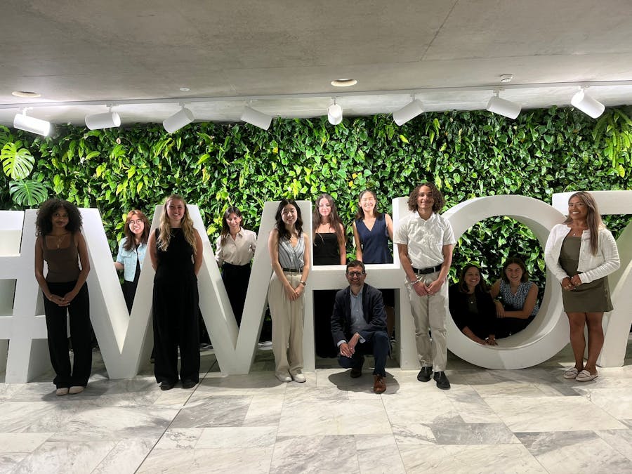 Students and staff stand next to 3D human-sized letters spelling #WHO7