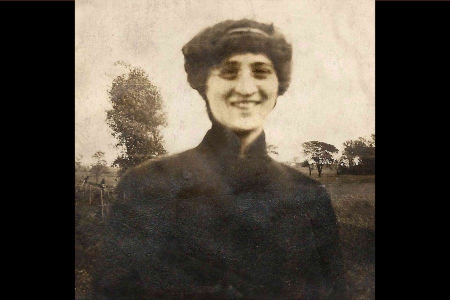 A vintage-seeming photograph of a smiling person in a country setting