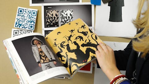 A student thumbs through a fashion marketing booklet they designed for a class.