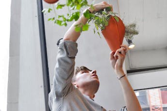 Student plants herbs into a hanging felt planter suspended in Parsons’ main building 