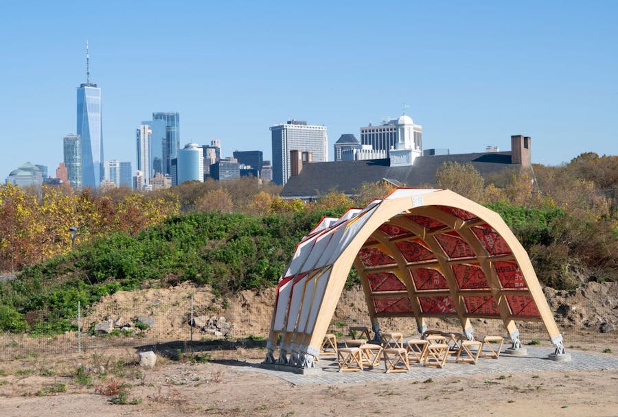 Seating shelter on Governors Island created by students in Parsons’ Design Workshop, with NYC skyline visible behind