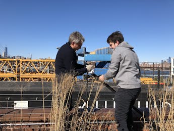 The New School’s Urban Systems Lab director Timon McPhearson and student install climate monitoring gear on a bridge in NYC