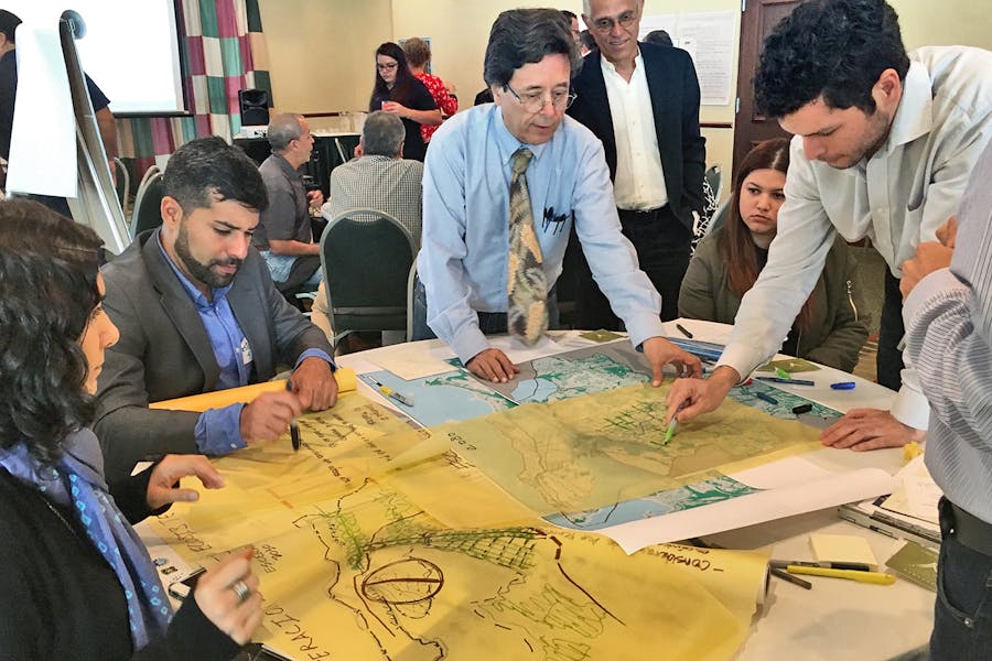 Members of the Urban Systems Lab convene around a table and review maps to predict future climate crises