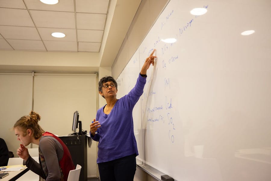 Professor Bhawani Venkataraman points to something on a board in front of a class