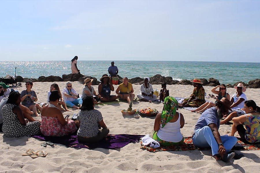 Young, diverse group of The New School’s Environmental Justice Movement Fellows gather on a beach to discuss climate activism