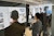 A student presents images of an interior design scheme created for a bookstore as students and faculty members look on, one with a hand raised to ask a question.