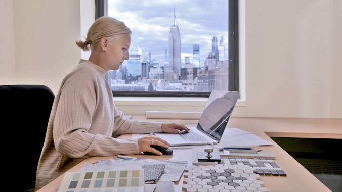 Woman working in the NYC office with the Empire State Building in background
