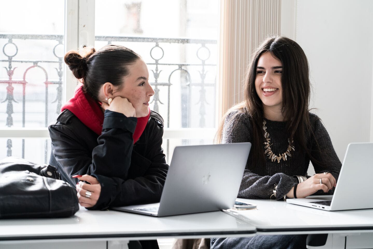 Two students talk in a classroom.