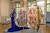 A fashion show including a blue velvet dress with antennae coming out the back, a purple and gold dress, and a dress featuring the face of Donatella Versace in a French art studio.