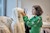 A student wearing a green blouse decorated with zebras works on a piece of muslin draped on the head of a mannequin.