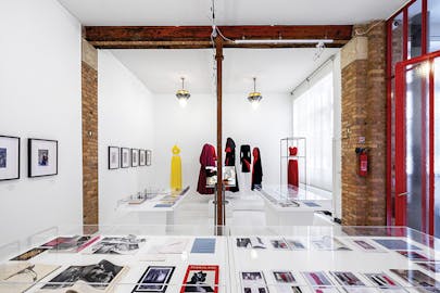 Curating Research Lab—a gallery with images displayed on walls and in tables with clothing displayed on mannequins in the background.