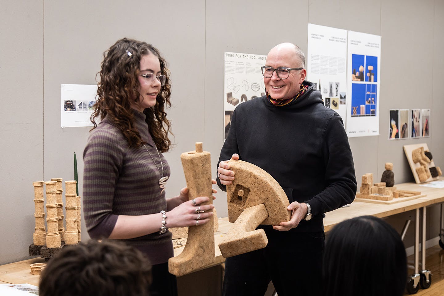 Daniel Michalik stands with BFA Product Design student Emily Quinn during a class presentation; both hold a piece of the student’s modular stool.