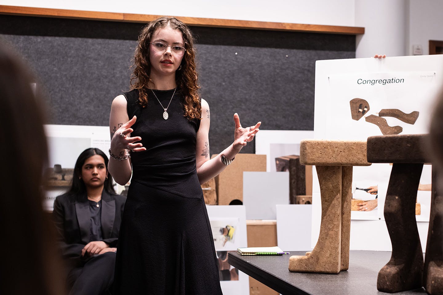 Emily Quinn stands before the competition judges explaining her modular cork stool design.