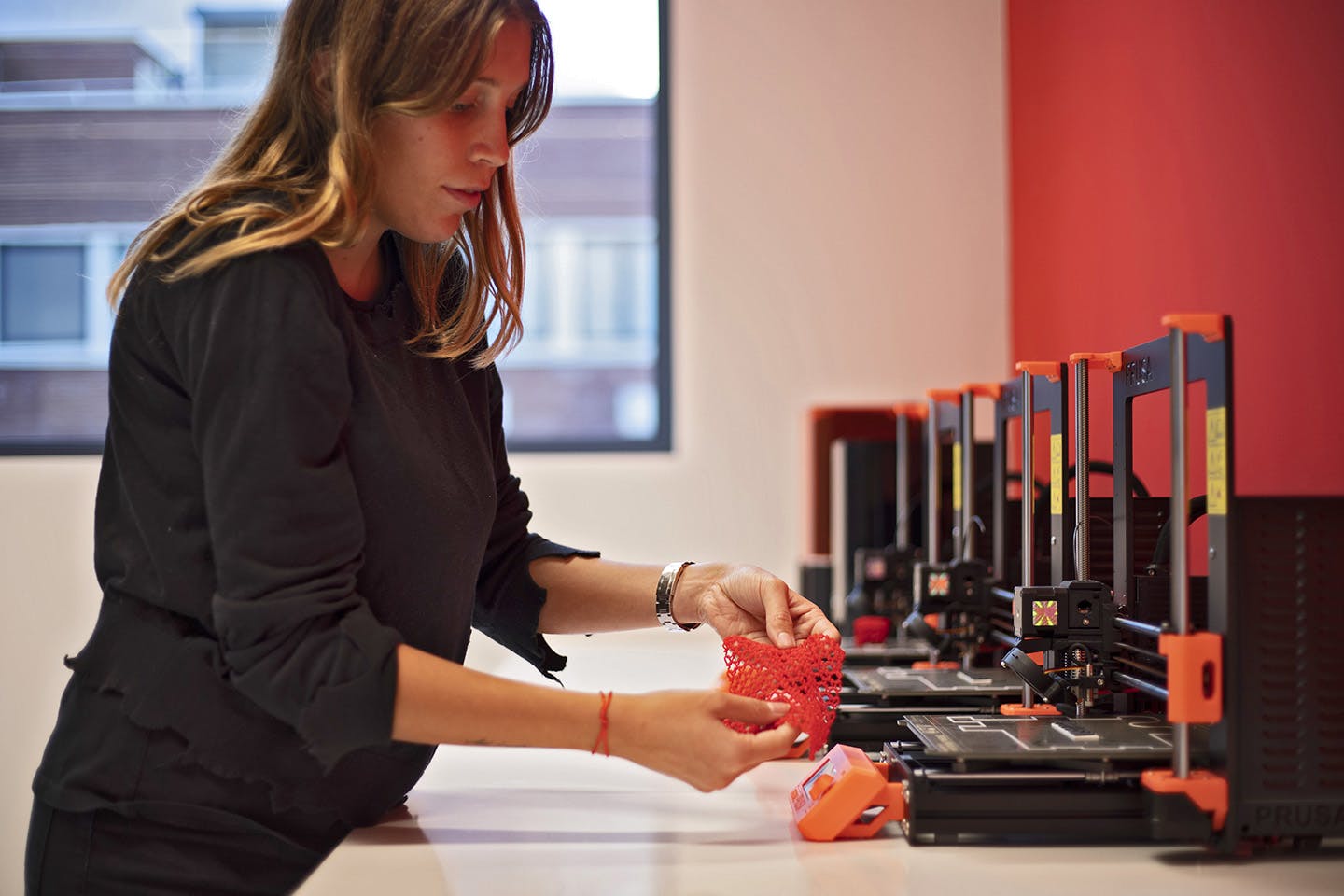 A student working with 3D printers in the main studio space.