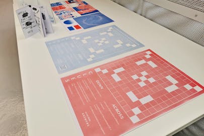 Two abstract Riso prints on a table, one is blue and one is red.
