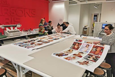 A group of students work with a professor to produce large-format prints for an exhibition.