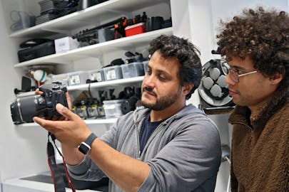 A technician shows a student a camera at the Equipment Checkout Library.