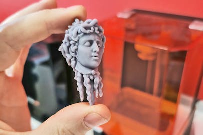 A closeup of a 3D print of the head of Medusa being held by a student. 