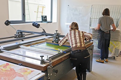 Two students working in the screen printing making space.