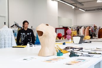 A Fashion Studio at Parsons Paris’ Romainville campus with projects on a table and a student walking across the studio in the background.