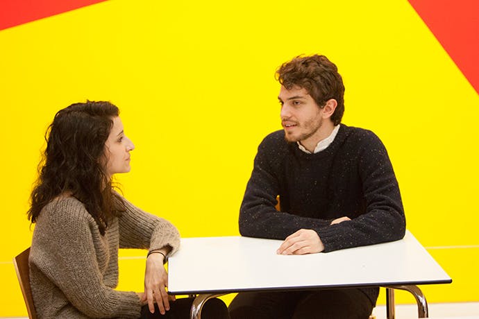 Two students sitting talking at table
