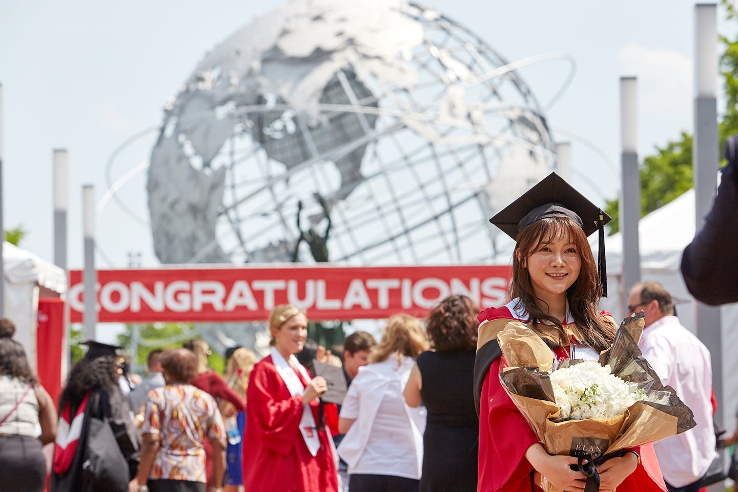 A New school graduate holding a bouquet of white flowers
