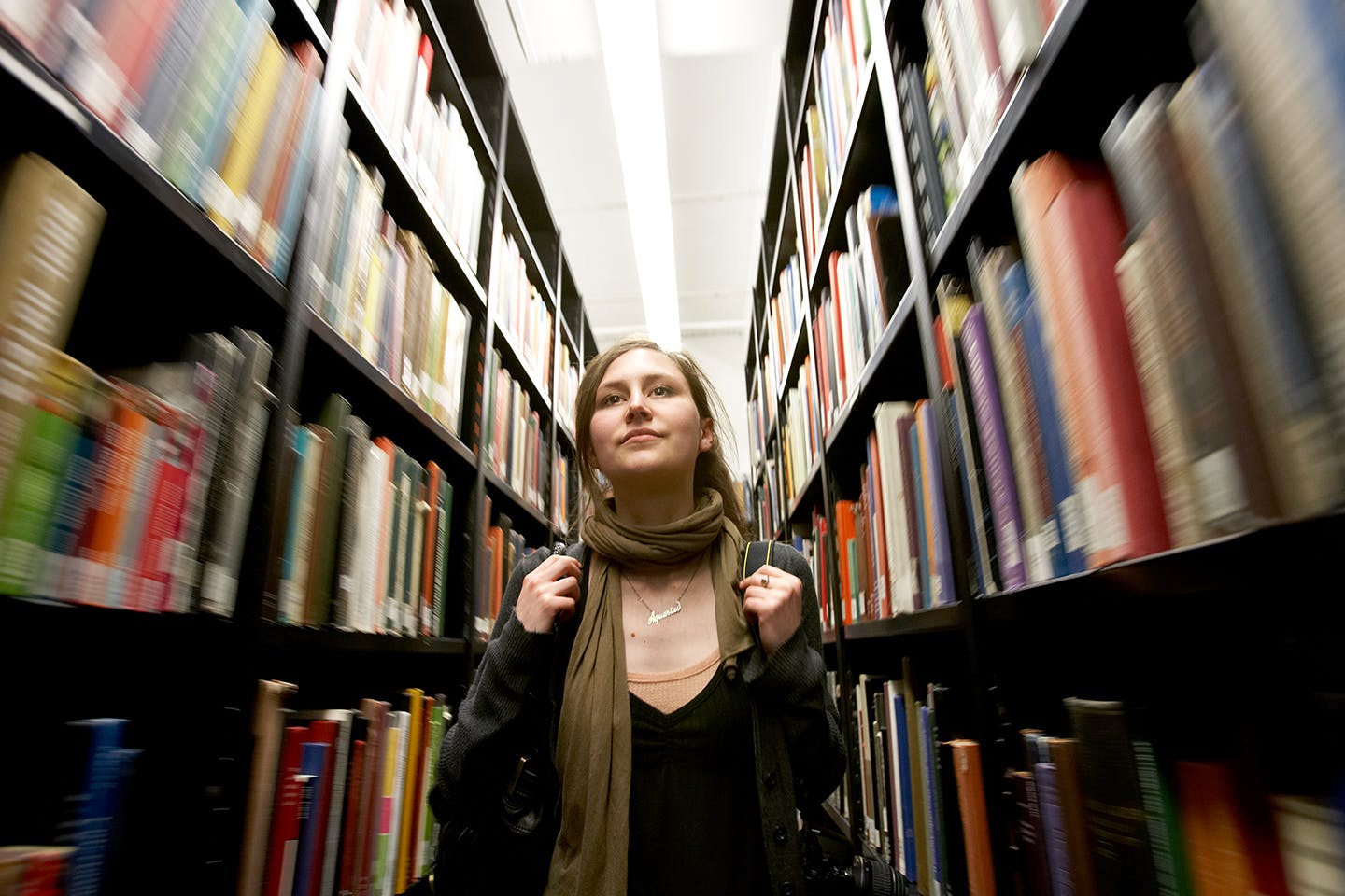 Student walking in a library hall of books