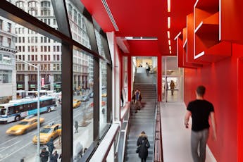 Interior hallway of University Center building showing people walking up stairs and Fifth Avenue outside windows