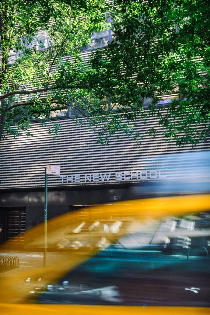 Front of Alvin Johnson building/J.M. Kaplan Hall with tree and passing yellow cab