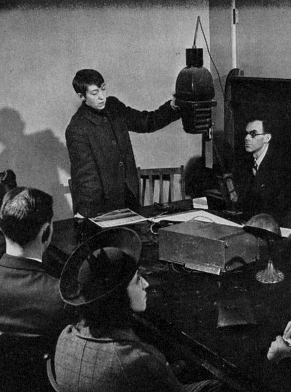 Photographer Berenice Abbott stands in front of her seated students, teaching photography in 1934