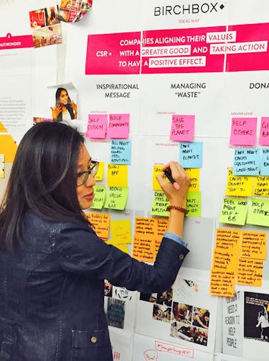 A woman writes on sticky notes while talking to another woman