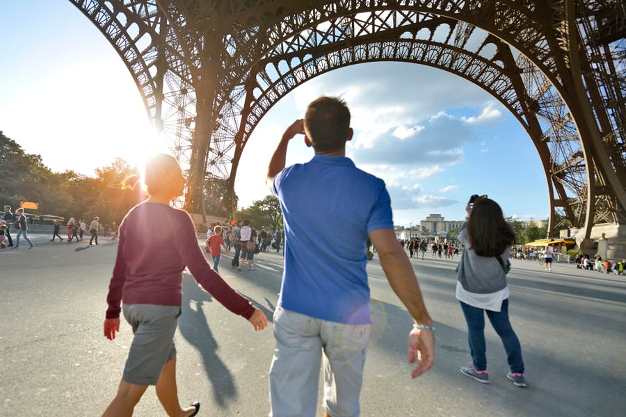 People look at the Eiffel tower while the sun shines