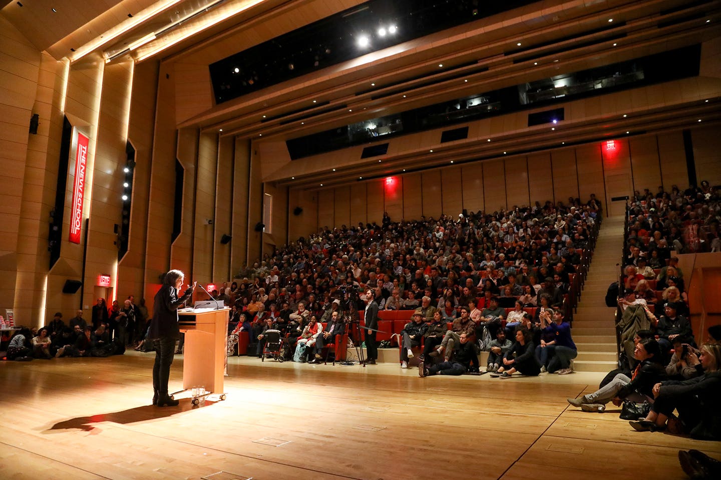An auditorium full of people listens to a speaker.