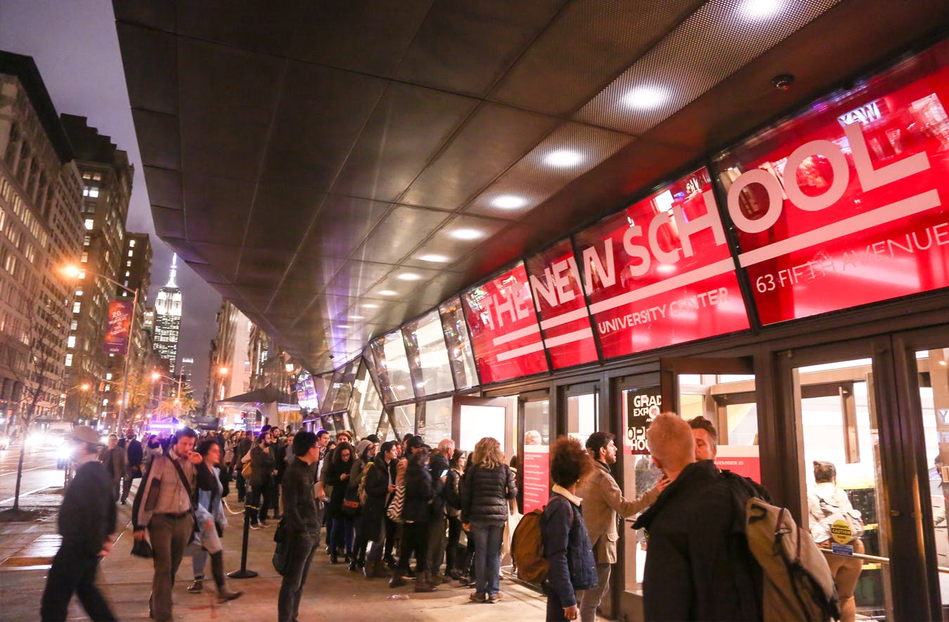 Several people queue up at front of the University Center at night.