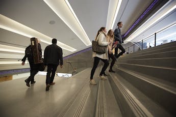 Students move up and down a modern concrete staircase with sharp angles and striking lighting.