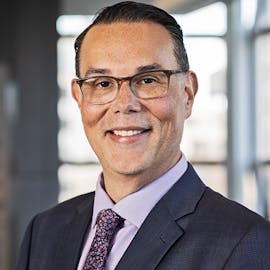 Vice Provost for Student Success and Engagement Rob Mack in suit and tie with glasses in front of window