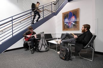 Students relax in the Jazz Lounge, one playing a guitar.