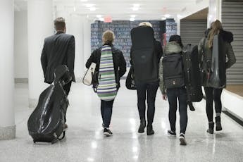A group of students walk down the hallway with their instruments.