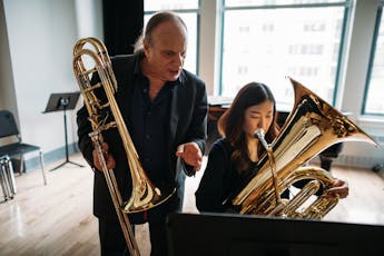 Dave Douglas instructs a seated student playing the tuba.