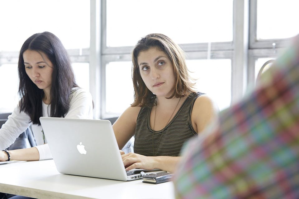 A student gives a curious look to someone off camera in a classroom.