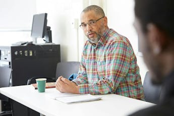 Professors talks to students in a classroom.