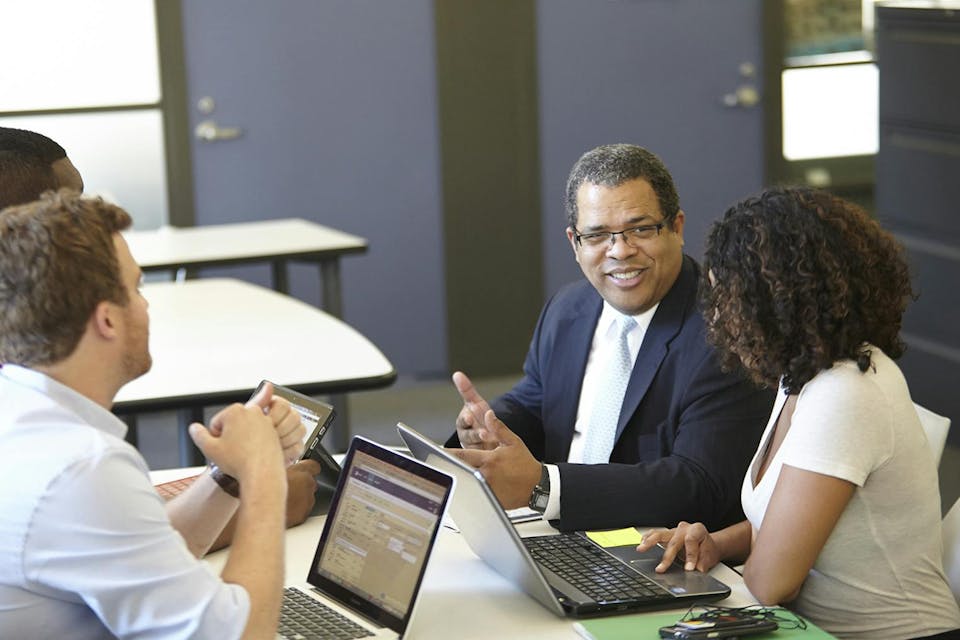 Students sit around a table with Professor Charles Allison