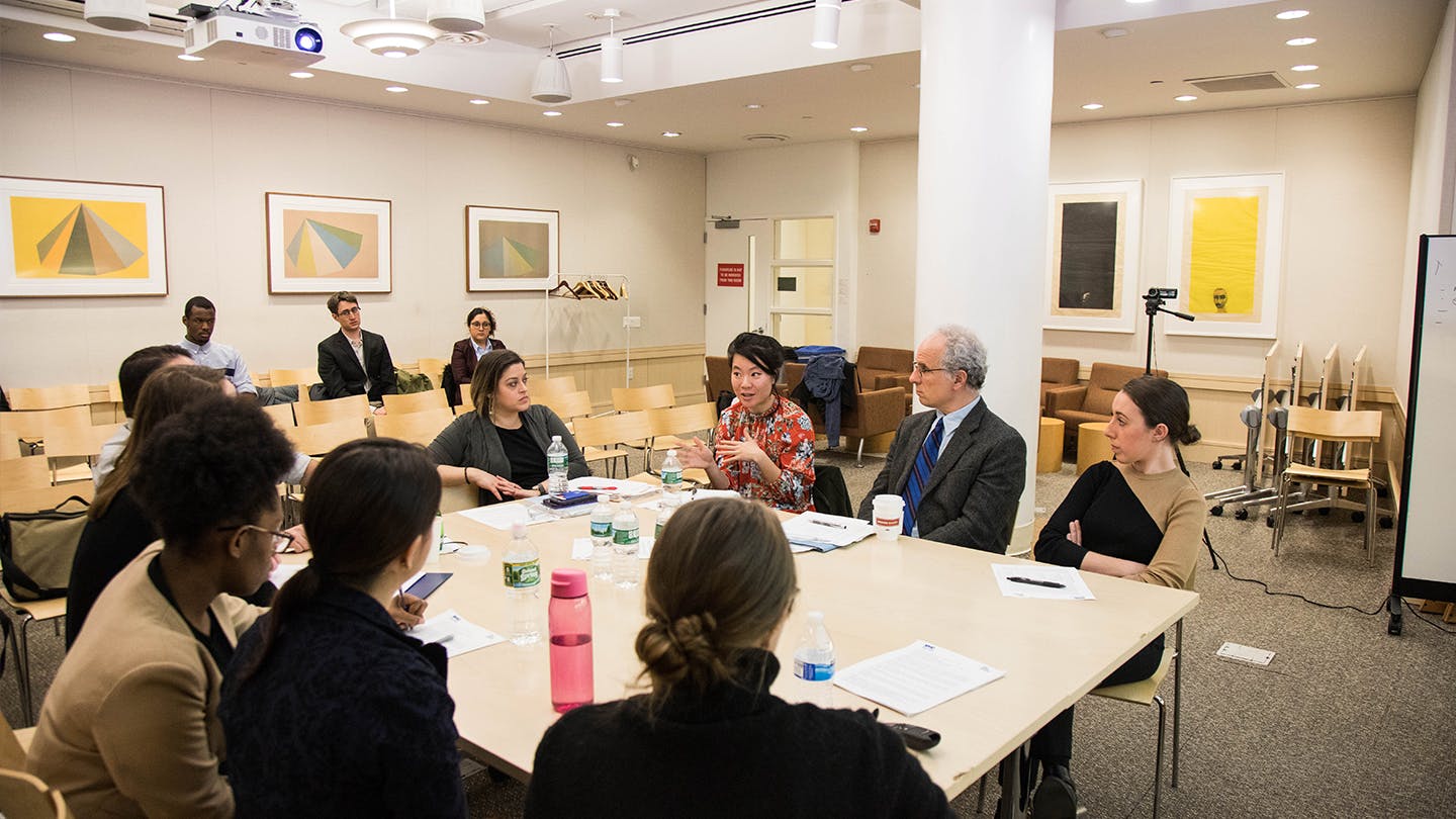 Public and Urban Policy faculty and students sitting around a table talking
